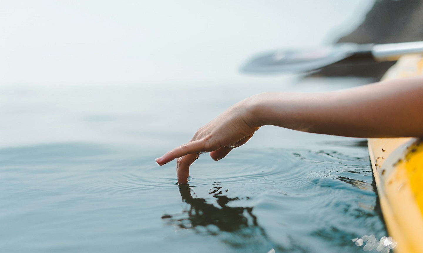 A person reaching down to touch the surface of water